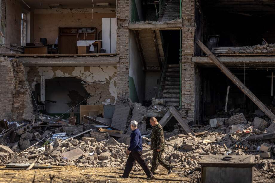 La gente pasa frente a un edificio con una fachada derrumbada en el complejo militar-industrial de la compañía Vizar, después de que el sitio fuera atacado durante la noche por ataques rusos, en la ciudad de Vyshneve, suburbios del suroeste de Kiev, el 15 de abril de 2022.