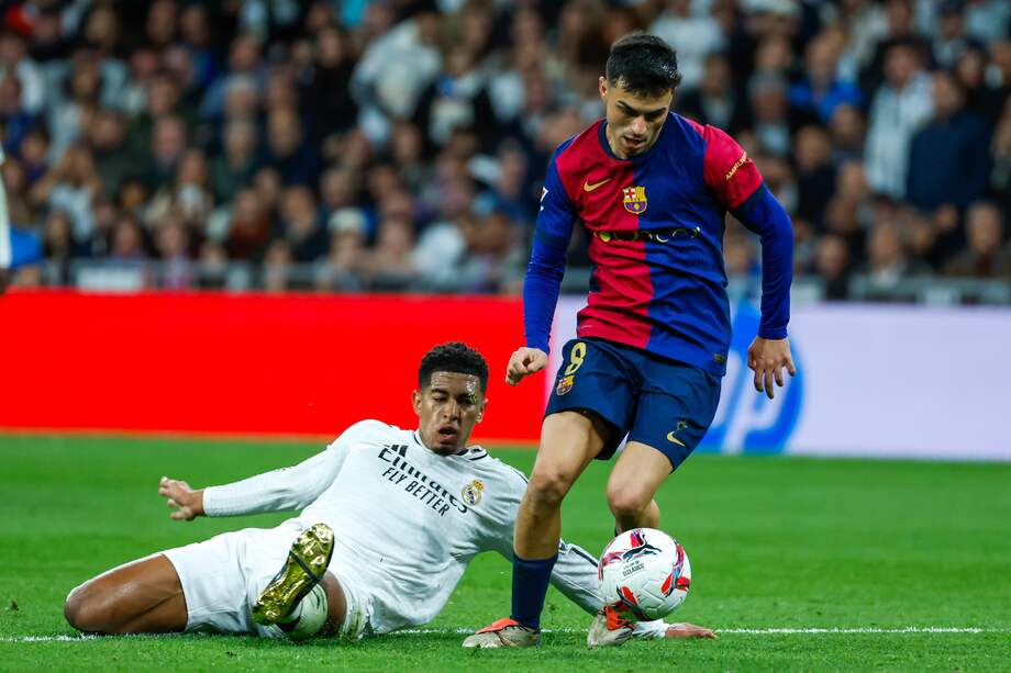 El centrocampista del Real Madrid Jude Bellingham (i) lucha con Pedri, del FC Barcelona, durante el partido de la jornada 11 de LaLiga EA Sports entre el Real Madrid y el FC Barcelona, este sábado en el estadio Santiago Bernabéu, en Madrid.