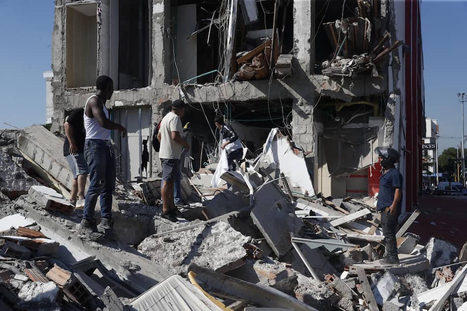 Personas caminan sobre los escombros de un edificio colapsado este lunes, en Cali (Colombia). Al menos 20 edificios sufrieron graves daños por consecuencia del terremoto de magnitud 7,4 que sacudió la mayor parte del país, con epicentro en la zona del Pacífico. EFE/ Ernesto Guzmán