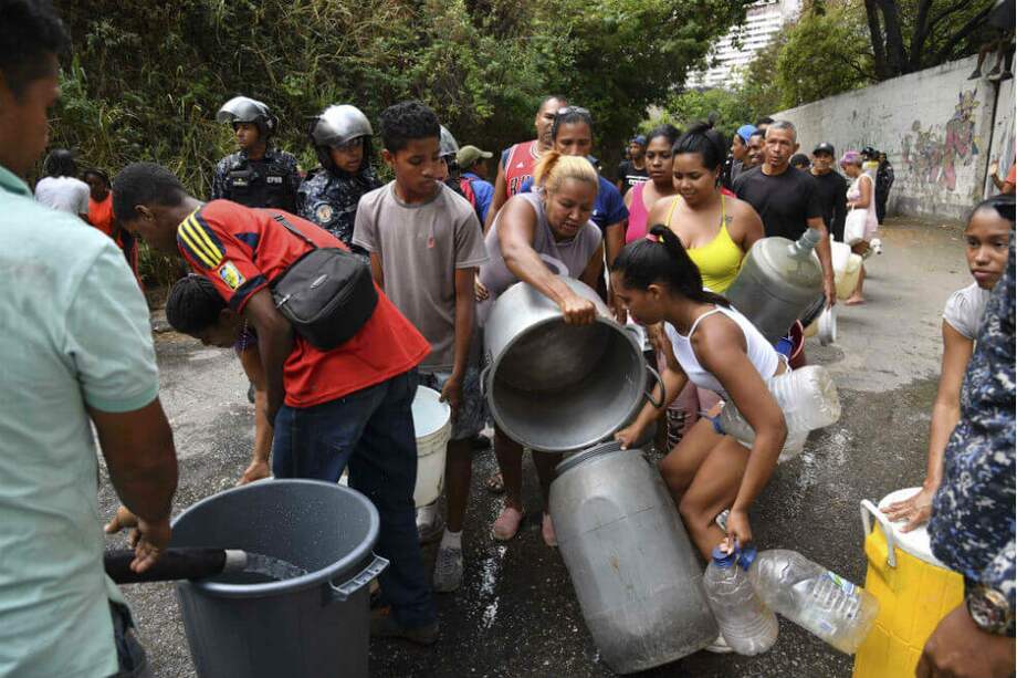 Habitantes de sectores periféricos de Caracas comparten agua hoy lunes. Gran parte del país también está sin energía eléctrica. / AFP