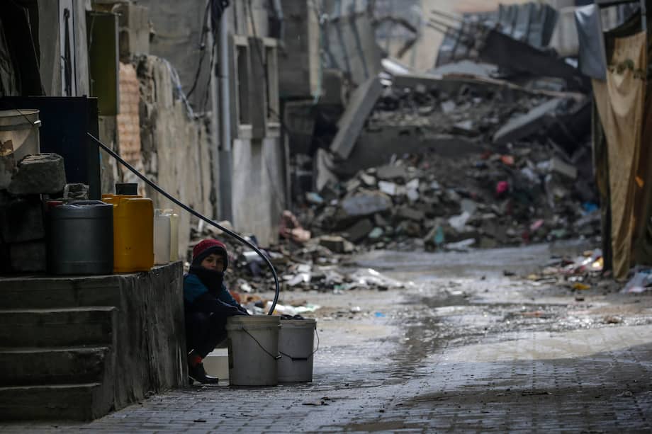 Un niño llena un cubo con agua entre los escombros de casas destruidas durante una operación militar israelí en el campo de refugiados de Al Nusairat, en el sur de la Franja de Gaza, este lunes.