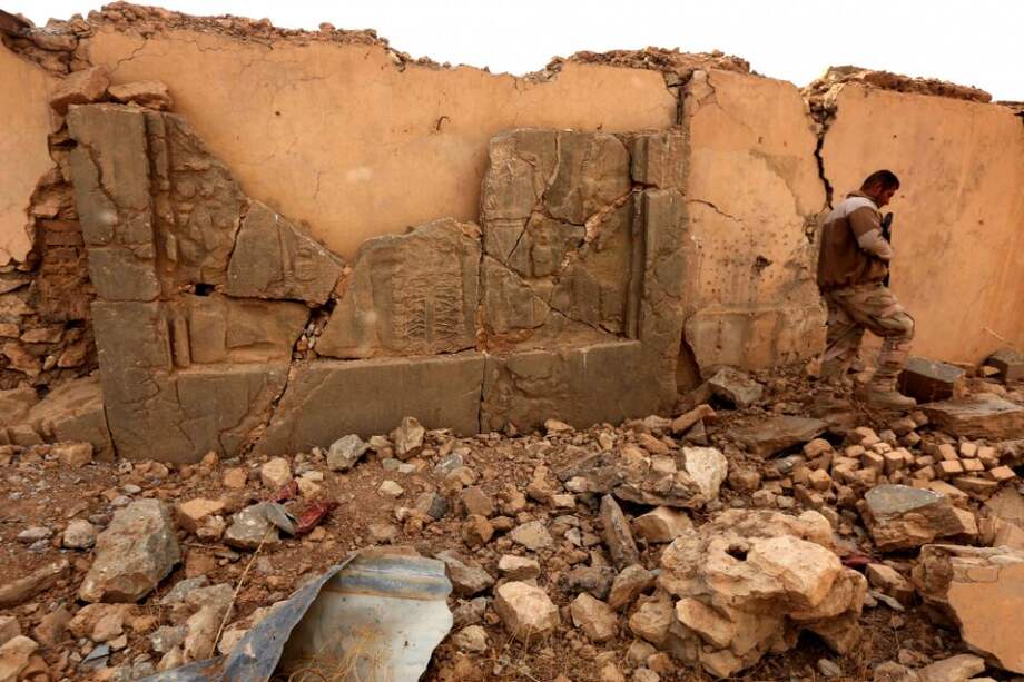 Un soldado iraquí camina entre las ruinas de Nimrud tras la recaptura de la ciudad, el 13 de noviembre. Este es uno de los paneles destrozados por el Estado Islámico. / AFP