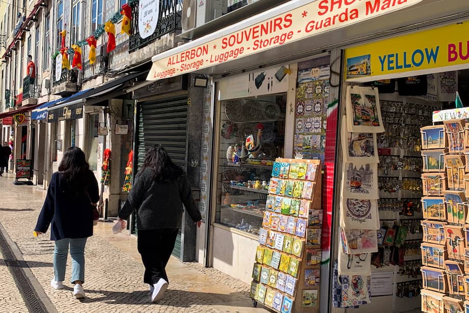 Dos jóvenes pasean junto a una de las decenas de tiendas de 'souvenirs' del centro de Lisboa.