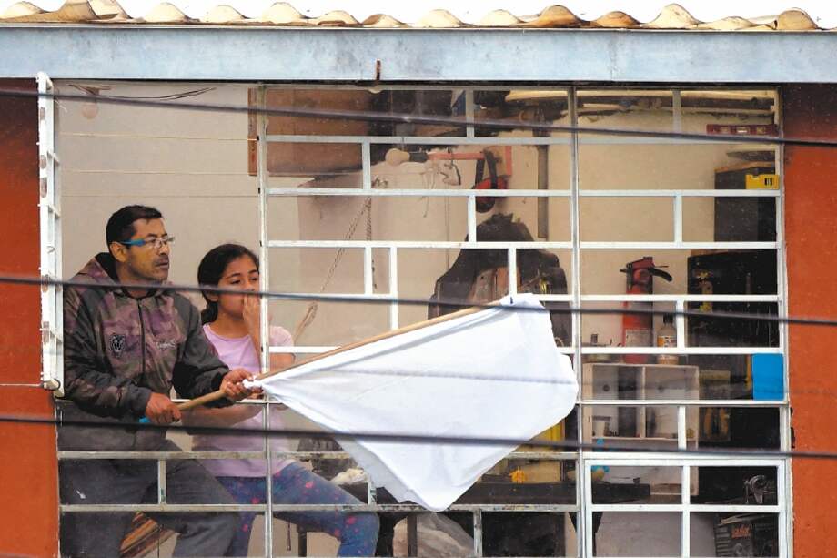 Local residents display a white flag as demonstrators clash with riot police during a protest against the government of Colombian President Ivan Duque, in Facatativa, Colombia, on May 31, 2021. / AFP / Raul ARBOLEDA