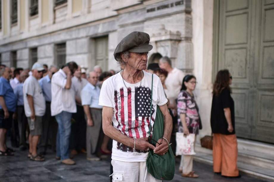 Un hombre espera en el centro de Atenas a la salida de uno de los bancos que reabrieron esta semana. / AFP