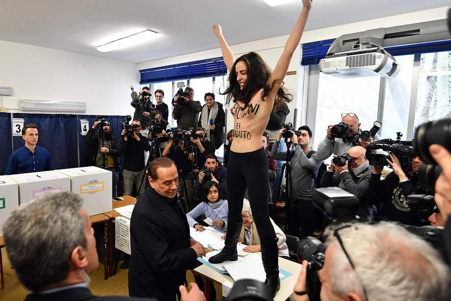 Una protestante del grupo Femen sorprende al exprimer ministro Silvio Berlusconi durante la jornada de votación en Milán, Italia. / EFE
