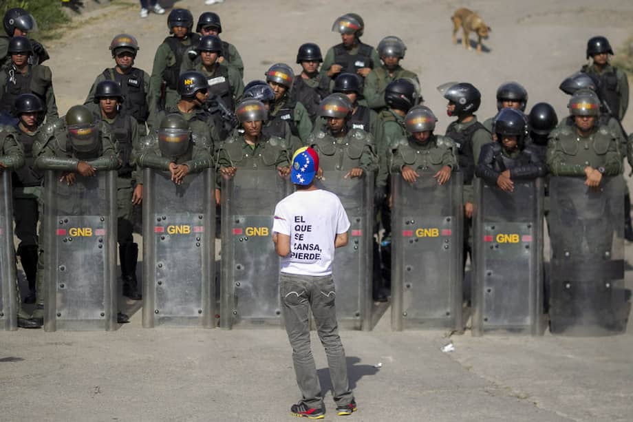Archivo. Un manifestante protesta frente a integrantes de la Guardia Nacional Bolivariana (GNB) durante una protesta de la oposición venezolana con la consigna en marzo de 2014.