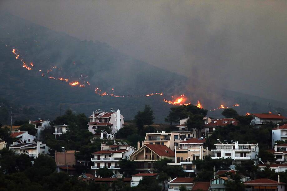 Un incendio se acerca a las casas en el monte Penteli, en el noreste de Grecia, el lunes.