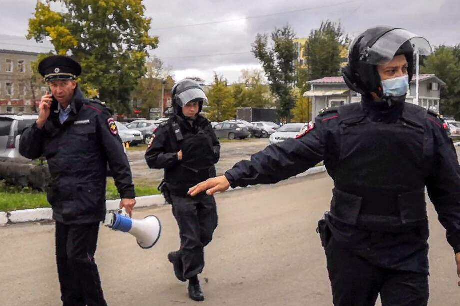 Los oficiales de policía vigilan mientras los estudiantes evacuan un edificio del campus universitario de Perm