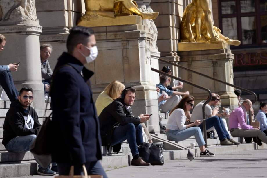 People sit on the steps of the Royal Dramatic Theater in Stockholm, Sweden, Wednesday April 22, 2020, keeping their distance amid the coronavirus COVID-19 outbreak. (Janerik Henriksson / TT via AP)