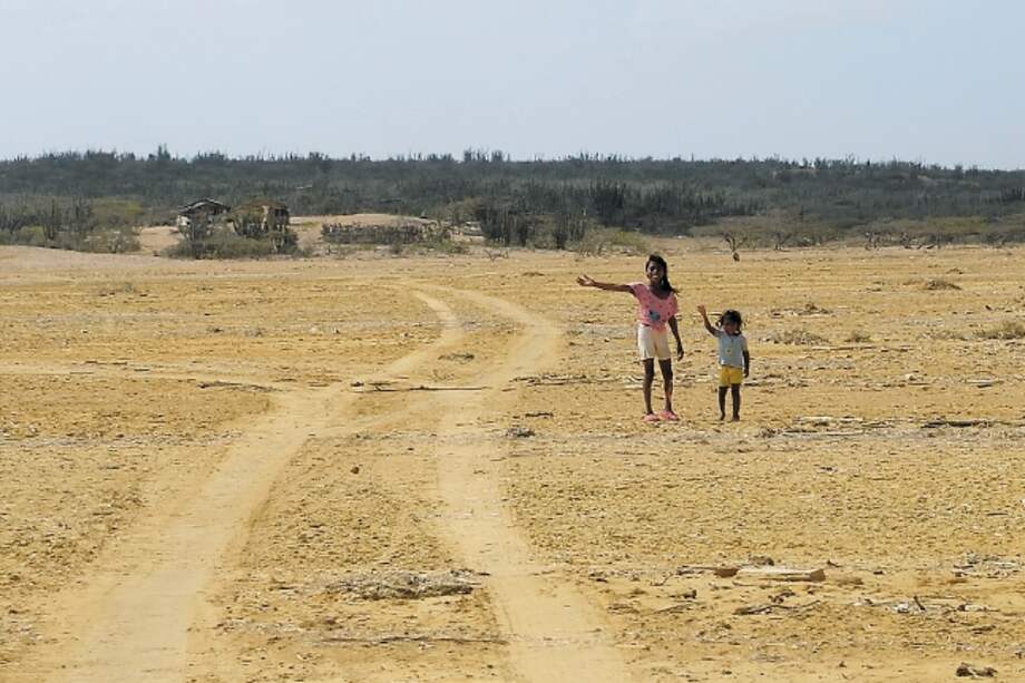 Dos niñas wayúu esperan en uno de los peajes humanos el paso de carros de turismo para pedir comida o agua. / Natalia Pedraza Bravo.