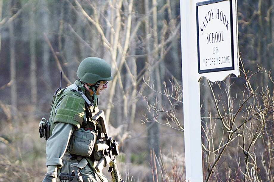 Un miembro de la policía fuertemente armado llega a la escuela Sandy Hook. / AFP