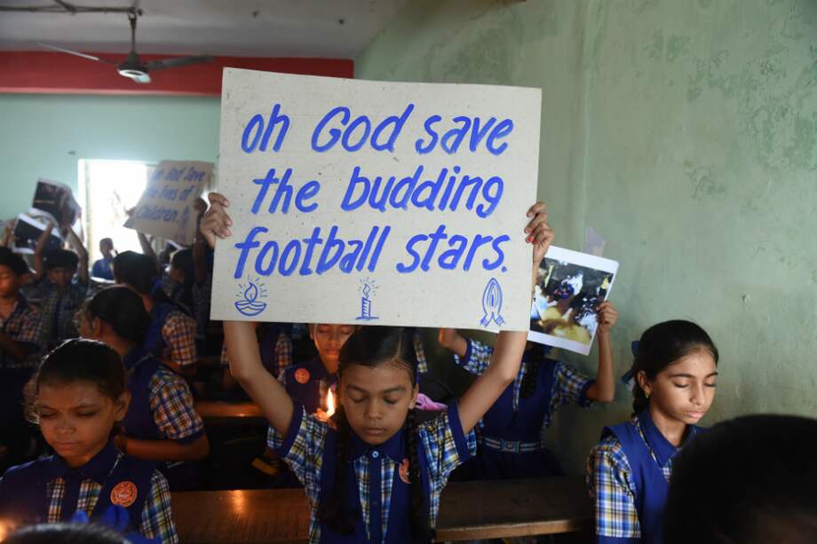 Un estudiante indio sostiene un cartel que dice "Oh Dios salva nuestras estrellas nacientes" en referencia a los jóvenes futbolistas atrapados. / AFP