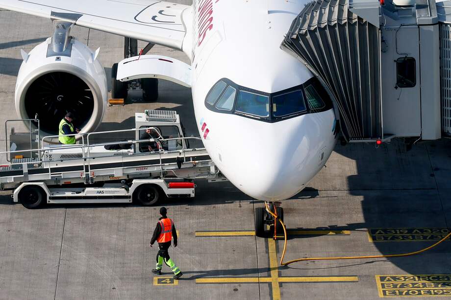 Un trabajador camina por la pista junto a un avión en tierra en el aeropuerto de Berlín-Brandeburgo, en Schönefeld, Alemania.