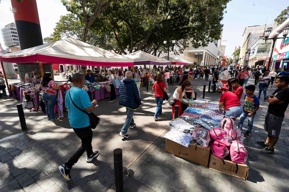 Unas personas caminan por una calle rodeada de ventas ambulantes en Caracas (Venezuela).