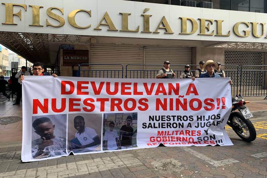 Dos personas sosteniendo un cartel en los exteriores de la Fiscalía Provincial del Guayas con el mensaje "devuelvan a nuestros niños", en alusión a los cuatro menores desaparecidos el 8 de diciembre en Guayaquil (Ecuador).