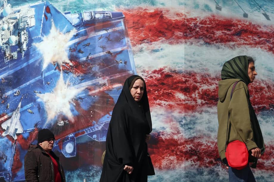 Iraníes caminan frente a una valla publicitaria antiestadounidense en la plaza Enqelab, en Teherán, Irán, el 16 de febrero de 2026.