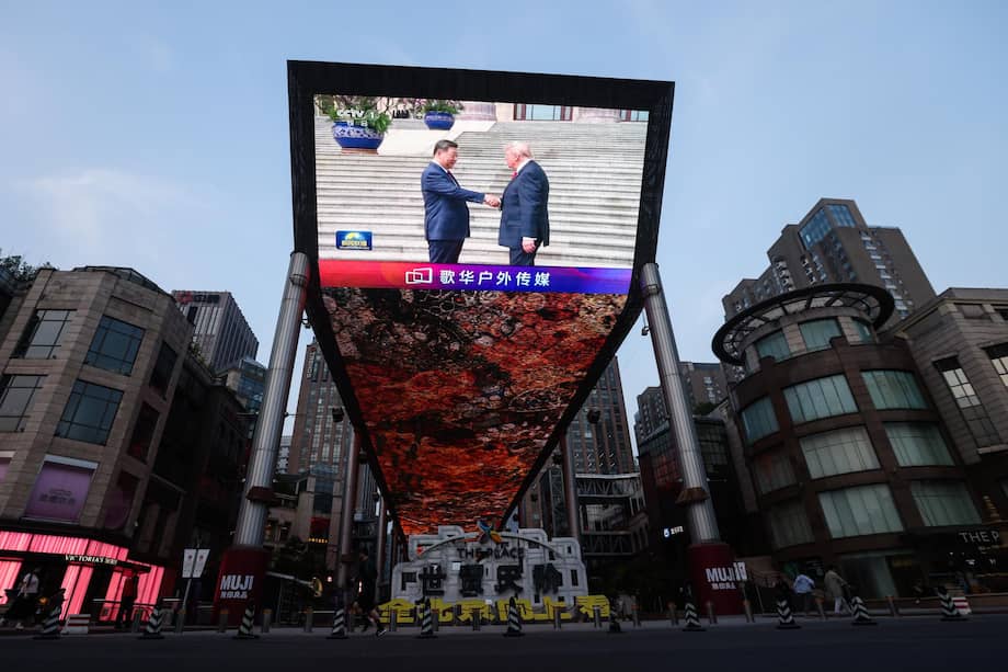 Una pantalla muestra al presidente chino Xi Jinping estrechando la mano del presidente estadounidense Donald Trump.