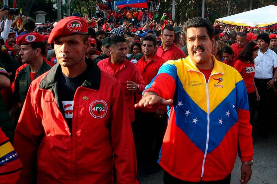 El vicepresidente venezolano, Nicolás Maduro (d), instruye al personal de seguridad durante el paso de carroza fúnebre que transporta el ataúd con el cuerpo sin vida del presidente venezolano, Hugo Chávez.