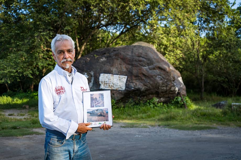 José Darío Nova, sobrino de Martha Vargas de Castro, frente a la gran roca de Armero. Sostiene un álbum fotográfico con imágenes antiguas del municipio.