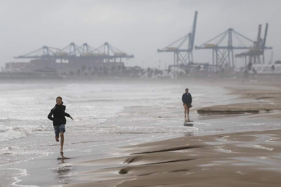 Dos personas pasean por la playa de la Malvarrosa durante las lluvias torrenciales que afectan a Valencia, España.