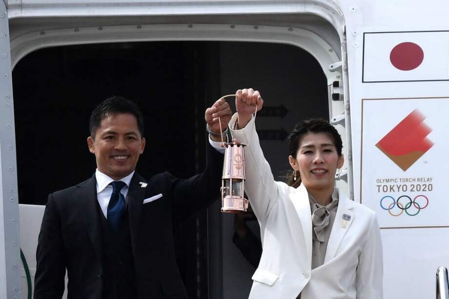 El tres veces campeón olímpico japonés de Judo, Tadahiro Nomura (i), y la triple medallista dorada de lucha libre, Saori Yoshida (d), sostienen la llama olímpica de Tokio 2020, que llegó desde Grecia. / AFP