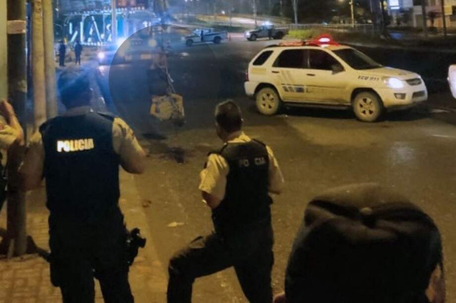 Contenido gráfico. Policías ecuatorianos observan los cuerpos que permanecen colgados de un puente peatonal en Durán, provincia de Guayas, Ecuador.