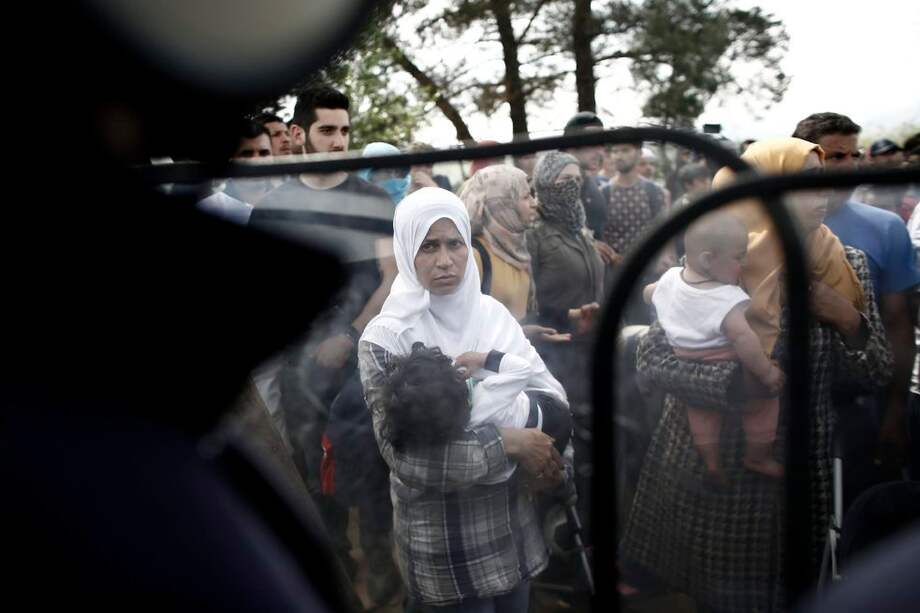 Una mujer con su hijo observa a los policías durante una manifestación que pide a Grecia la apertura de las fronteras a Macedonia. / EFE