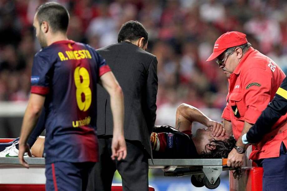 El jugador del Barcelona Carles Puyol (i), lesionado, es atendido durante el partido de la Liga de Campeones ante el Benfica / EFE