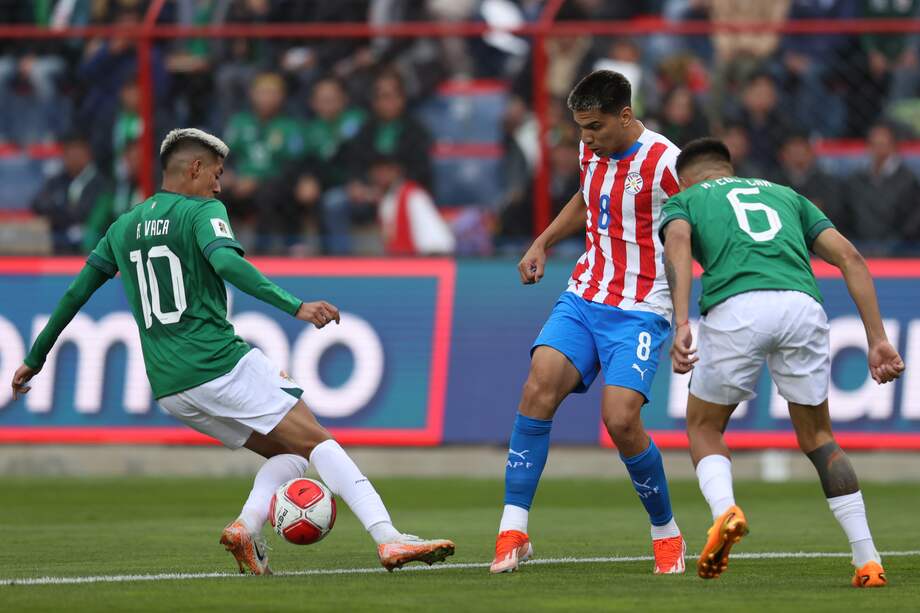 Ramiro Vaca (izq.) de Bolivia disputa un balón con Diego Gómez (centro) de Paraguay, durante el duelo entre Bolivia y Paraguay en el estadio Municipal de El Alto (Bolivia). EFE/ Luis Gandarillas