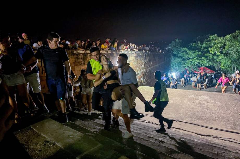 Unos hombres cargan a una mujer afectada tras un tiroteo registrado en un evento musical en San Bernardino (Paraguay).