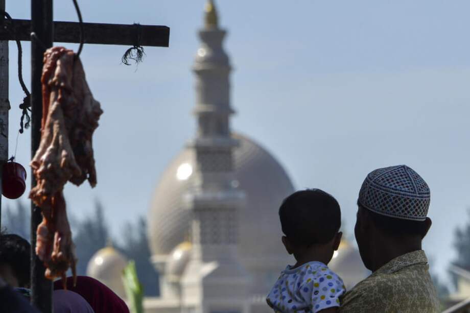 Un hombre y un niño en Banda Aceh (Indonesia) miran hacia una mezquita, mientras compran en un mercado local para dar la bienvenida al mes sagrado de Ramadán. / AFP