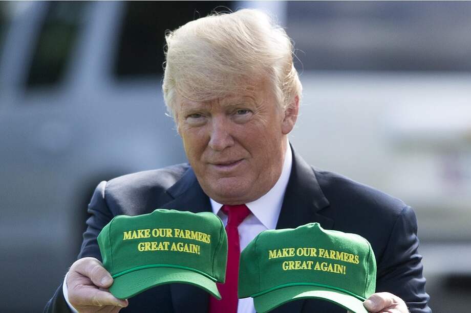 El presidente Trump muestra en el patio de la Casa Blanca unas gorras con el letrero "hacer que nuestros granjeros vuelvan a ser grandes" previo a un viaje a Indiana para hacer campaña por los republicanos. / EFE