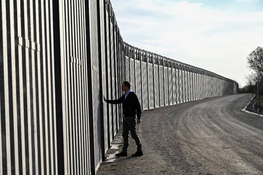 El primer ministro griego, Kyriakos Mitsotakis, camina junto al muro antimigrantes de Grecia en la frontera con Turquía.