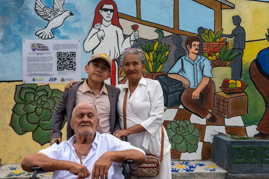 Silvia Segura y Eduardo Álvarez, acompañados de uno de sus nietos menores, frente al mural de isnos (Huila) en el que está representado su nieto Miller Blandón.
