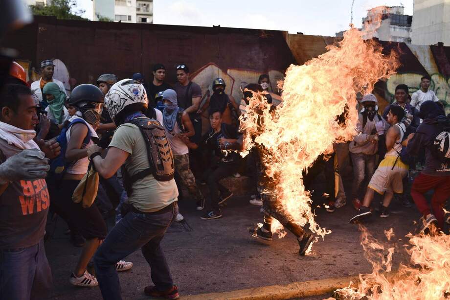 Un grupo de manifestantes contra Maduro el 20 de mayo de 2017 prende fuego a Orlando Figuera, que falleció poco después.
/ AFP