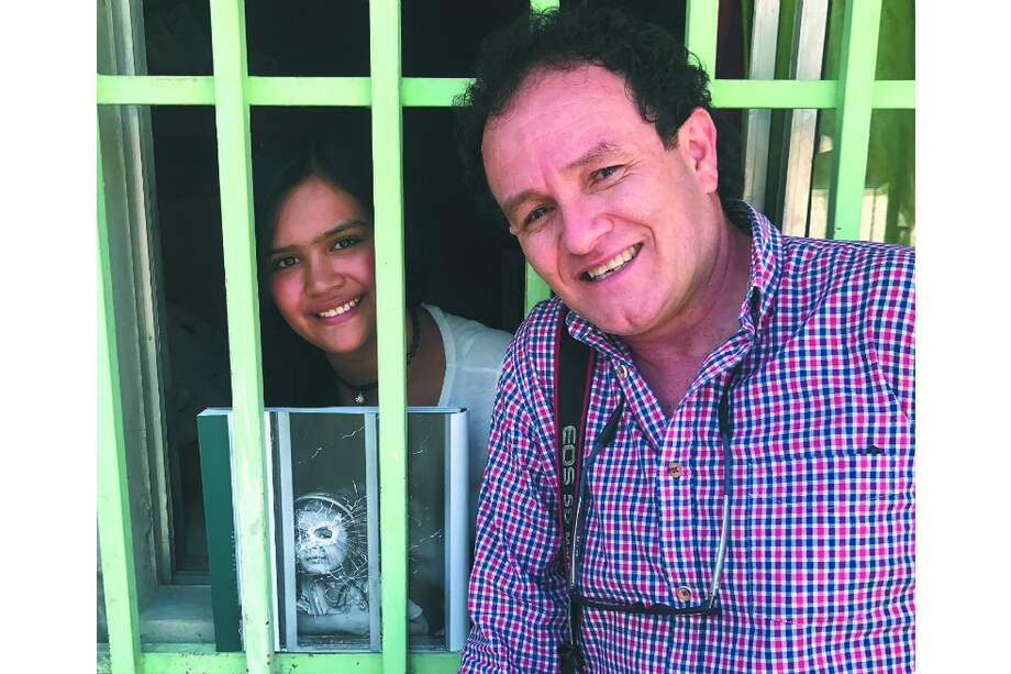 El reportero Jesús Abad Colorado junto a una niña de la Comuna 13 de Medellín, en la misma ventana donde la fotografió años atrás cuando su casa fue blanco de un tiroteo. Una de las historias que reconstruye el documental.
/ Cortesía Caracol Tv