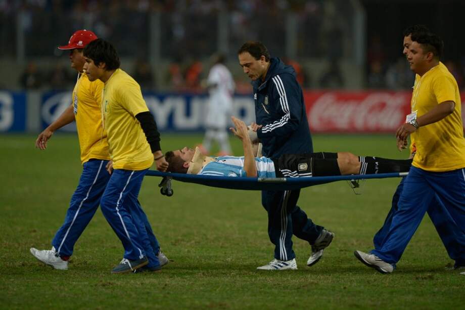 Momento en el que Fernando Gago es retirado de la cancha en camilla, tras sufrir un fuerte golpe en la cabeza. / AFP