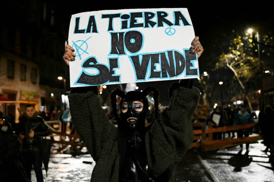 Un manifestante muestra un cartel que dice en español: "La tierra no está en venta" frente a una barricada durante una protesta en la Avenida Mayo, cerca del Congreso Nacional en Buenos Aires, el 6 de agosto de 2026, mientras los senadores debaten un proyecto de ley sobre la inviolabilidad de la propiedad privada.