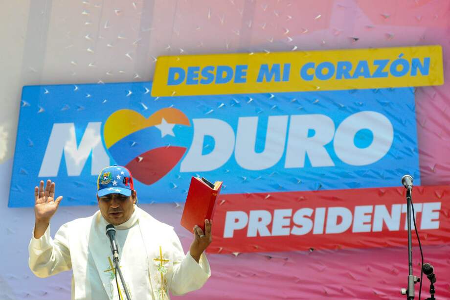 Un sacerdote hace una oración por el presidente encargado y candidato oficial, Nicolás Maduro, que ayer llenó el centro de Caracas con miles de chavistas. / AFP