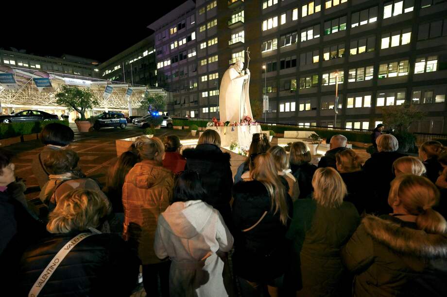 Los fieles asisten a una oración del Rosario por la salud del Papa Francisco ante una estatua del Papa San Juan Pablo II en el exterior del Hospital Gemelli en Roma, Italia, el 27 de febrero de 2025.