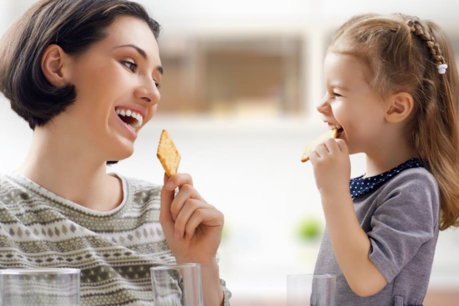 Mamá sonriendo con su pequeña mientras comen galletas