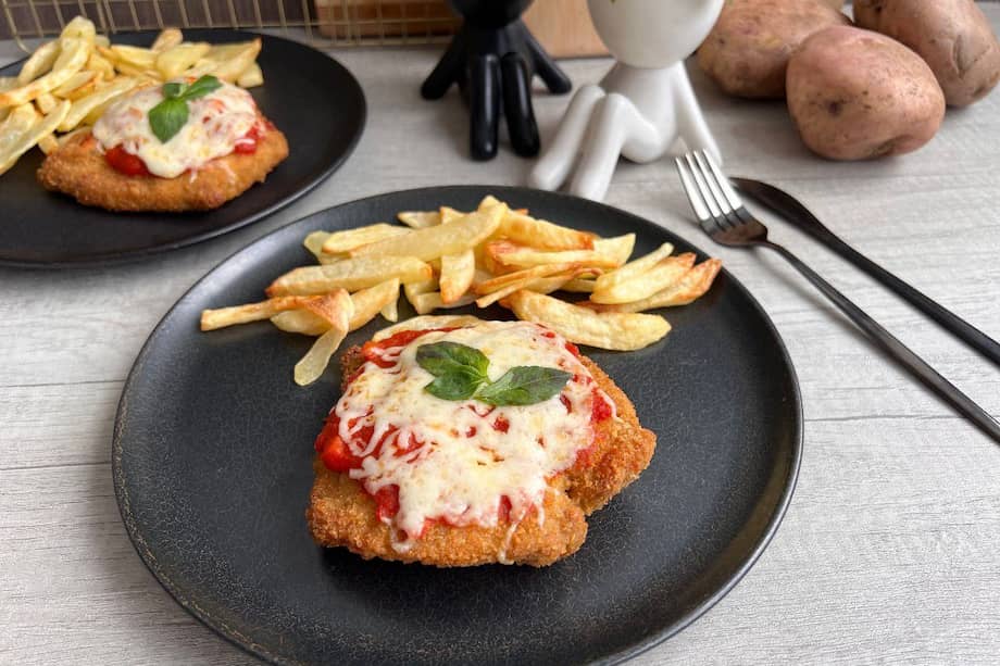 Acompaña esta milanesa de pollo con salsa napolitana y como guarnición papas a la francesa.