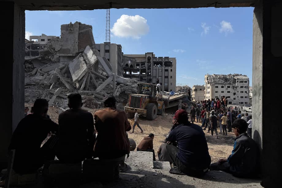 Un grupo de gazatíes observa los trabajos de rescate de cuatro personas (un padre y sus tres hijas), de entre los escombros tras un ataque aéreo israelí contra el edificio donde se refugiaban.