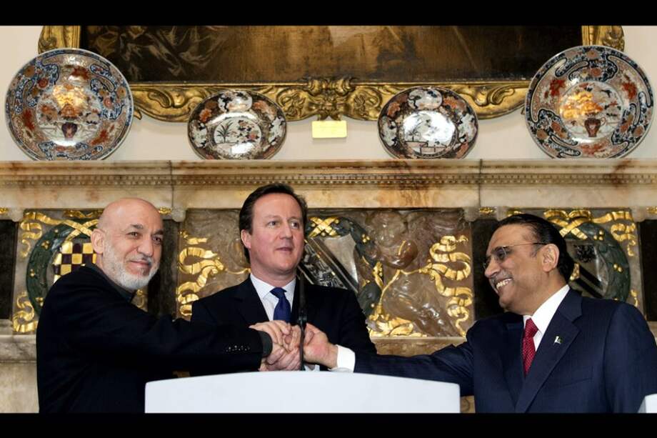 El primer ministro del Reino Unido David Cameron estrecha sus manos con el presidente de Afganistán, Hamid Karzai (izq) y el presidente paquistaní, Asif Ali Zardari. / AFP