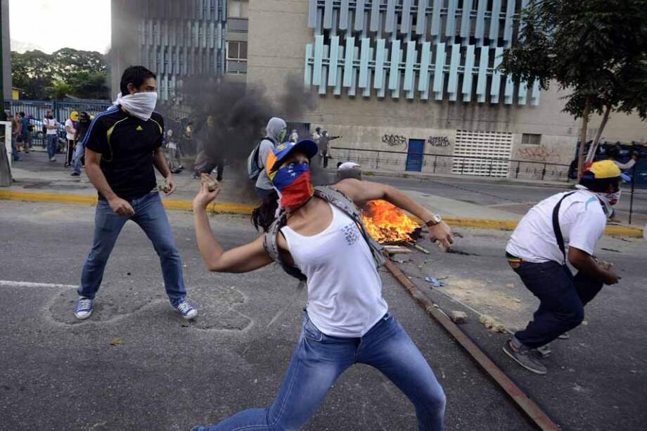 Activistas de oposición durante una manifestación el año pasado contra el gobierno venezolano. Los manifestantes le lanzan piedras a un escuadrón de la policía en Caracas. / AFP