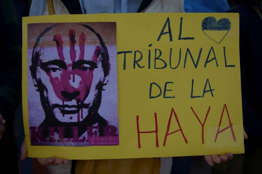 Una mujer sostiene un cartel que representa al presidente ruso Vladimir Putin y dice "A la corte de La Haya" durante una protesta contra la invasión rusa de Ucrania.