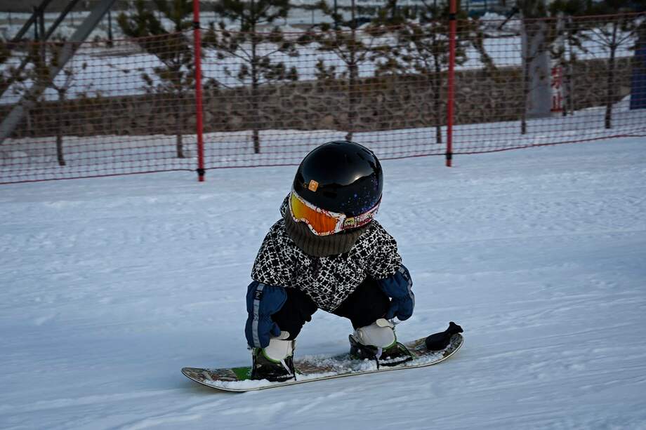 Esta foto tomada el 24 de noviembre de 2021 muestra a la niña Wang Yuji de 11 meses deslizándose por una pendiente en su tabla de snowboard en una estación de esquí en Zhangjiakou, en la provincia de Hebei, en el norte de China.