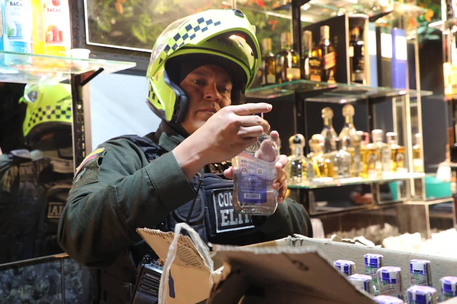 Uniformado inspecciona botellas de licor durante la intervención al bar “sindicato”.