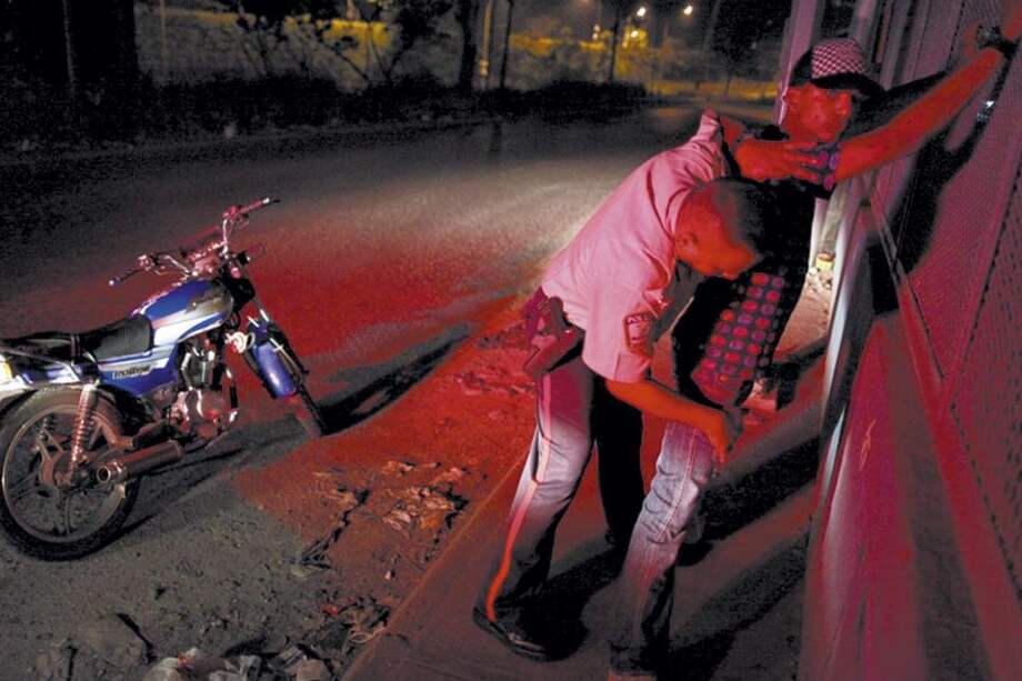 Un policía registra a un joven en el barrio Petare, uno de los más peligrosos del municipio caraqueño de Sucre.